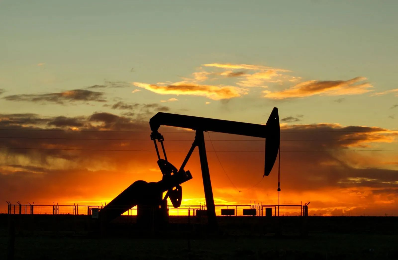 Oil and gas production well silhouetted at sunset
